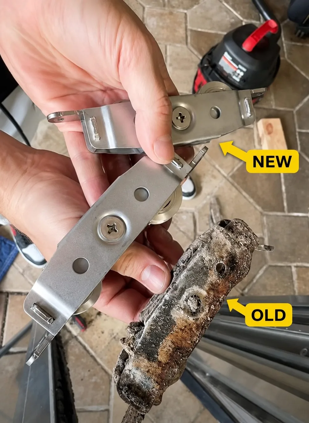 A technician holding a new sliding door roller beside a corroded old one